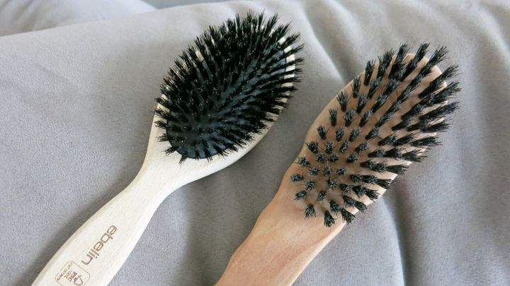 Zwei Haarb&uuml;rsten liegen auf einem grauen Stoff, bereit zur Pflege von Kopfhaut und Haaren f&uuml;r gesunden Glanz.