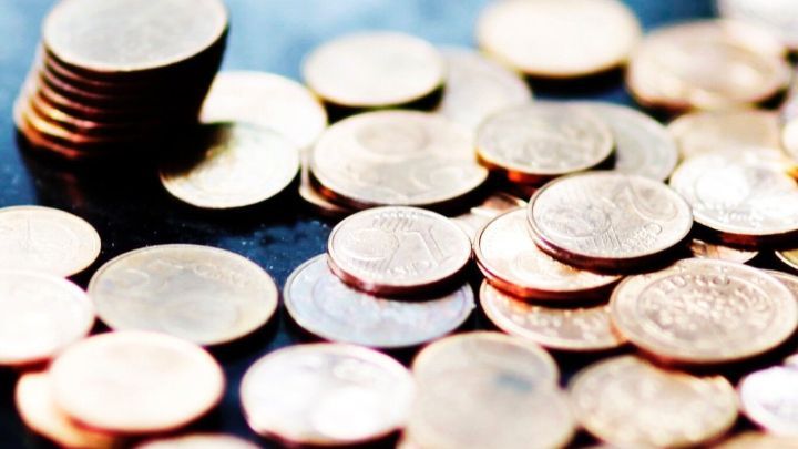 Eine Ansammlung von M&uuml;nzen liegt verstreut auf einer Oberfl&auml;che, mit einigen gestapelten M&uuml;nzen in einer Ecke.