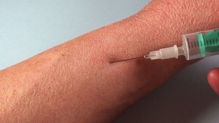 Eine Hand spritzt eine Injektion in den Arm, um Desinfektion durchzuf&uuml;hren und Hygiene sicherzustellen.