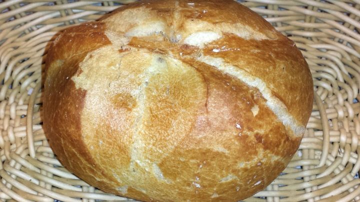 Ein knuspriges Aufbackbr&ouml;tchen liegt in einem geflochtenen Korb und zeigt eine goldbraune, rustikale Oberfl&auml;che.