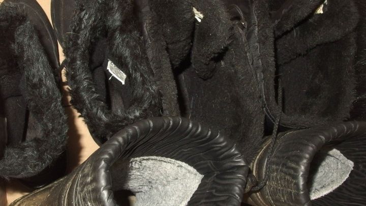 Schwarze Hausschuhe liegen ordentlich nebeneinander auf einer Braune Pappe, bereit f&uuml;r den Gebrauch oder die Lagerung.