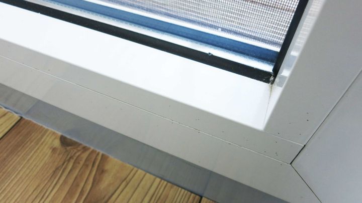 Ein wei&szlig;er Kunststoffrahmen wird gereinigt, w&auml;hrend er an einem Fenster mit Holzfu&szlig;boden steht.