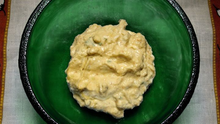 Ein cremiger Avocadodip liegt in einer gr&uuml;nen Sch&uuml;ssel auf einem Tisch, bereit zum Genie&szlig;en bei einem Snack.