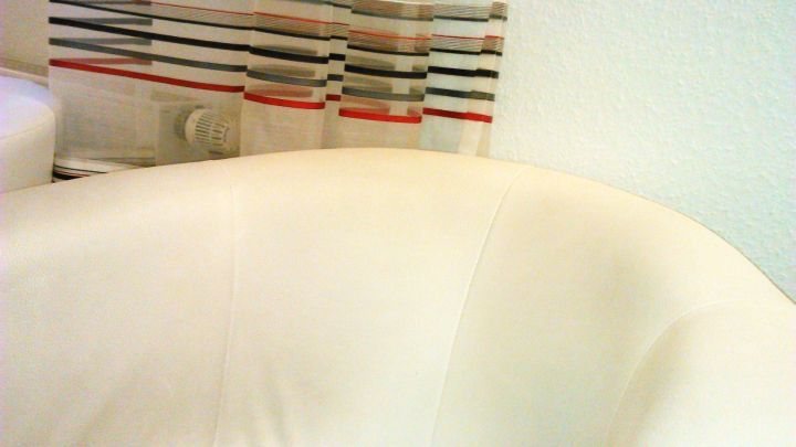 Ein wei&szlig;es Lederst&uuml;ck wird in einem hellen Raum betrachtet, umgeben von einem farbigen Vorhang im Hintergrund.