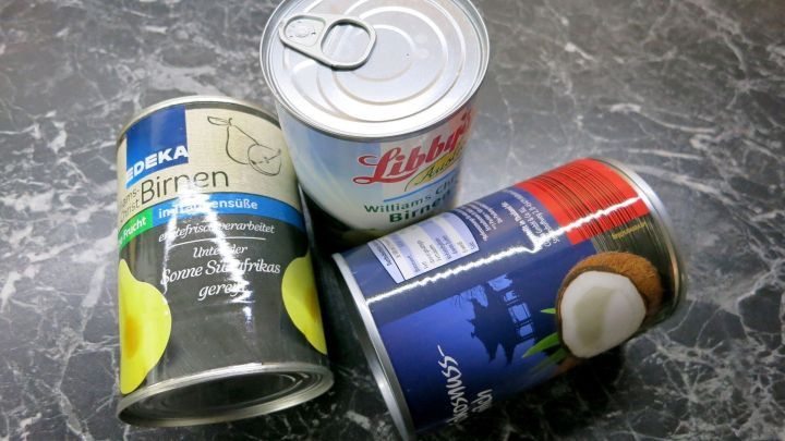 Leere Konservendosen liegen kreativ gestapelt auf einer dunklen поверхности, bereit f&uuml;r die Verwendung als Garten- oder Tischdeko.