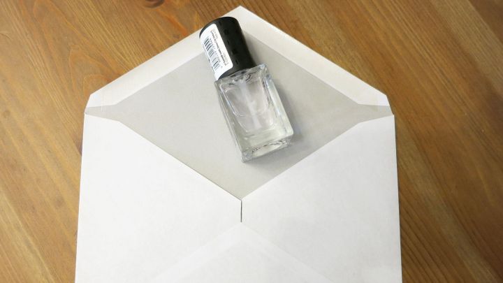 Ein Briefkuvert liegt auf einem Tisch, w&auml;hrend eine Flasche Kleber die Klappe sicher verschlie&szlig;t.