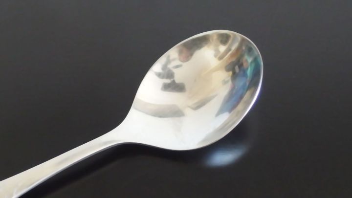 Ein silberner L&ouml;ffel liegt auf einer dunklen Oberfl&auml;che, bereit, zum Schlucken gegen Schluckauf eingesetzt zu werden.