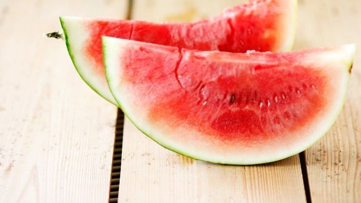 Saftige Melonenst&uuml;cke liegen auf einem rustikalen Holztisch und vermitteln einen erfrischenden, sommerlichen Genuss.