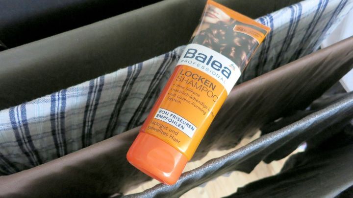 Haarshampoo liegt auf einem W&auml;schest&auml;nder mit Kleidung. Text auf der Flasche: &ldquo;Balea PROFESSIONAL LOCKEN SHAMPOO. Von Friseuren empfohlen. Lockiges und gewelltes Haar.&rdquo;