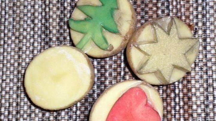 Ein kleiner Stempel aus roher Kartoffel mit verschiedenen Motiven, der auf einem Tisch zum Basteln und Dekorieren bereitliegt.