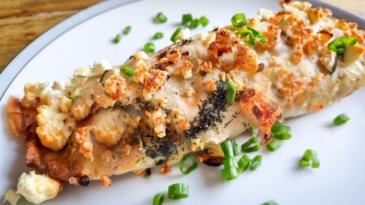 Die Pfannkuchenr&ouml;llchen zeigen gef&uuml;llte Teigrollen, die mit Feta-Creme und Kr&auml;utern garniert sind, angerichtet auf einem Teller.