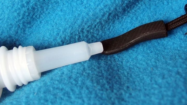 Ein Stoff-Zipper mit einem B&auml;ndel, der an einem wei&szlig;en Verschluss befestigt ist, liegt auf einem blauen Hintergrund.