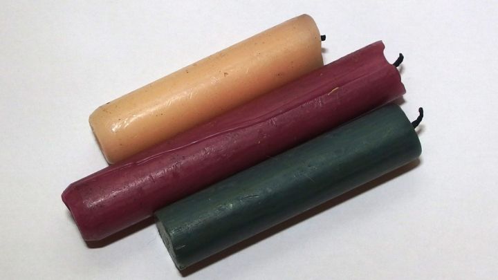 Drei Kerzenreste in verschiedenen Farben liegen auf einer wei&szlig;en Unterlage. Sie zeigen die Grundlage f&uuml;r Bohnerwachs.