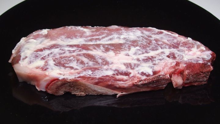 Ein gro&szlig;es St&uuml;ck rohes Fleisch liegt auf einem schwarzen Teller und wartet darauf, mit Meerrettich zubereitet zu werden.