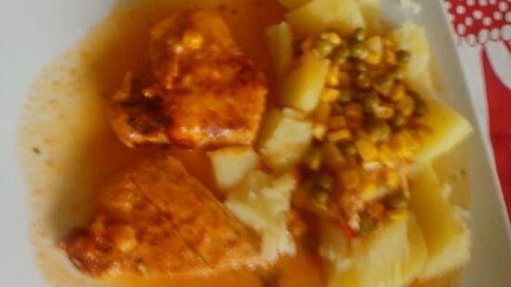 Zwei &uuml;berbackene Schnitzelst&uuml;cke liegen auf einem Teller, umgeben von Kartoffeln und einer bunten Sauce.