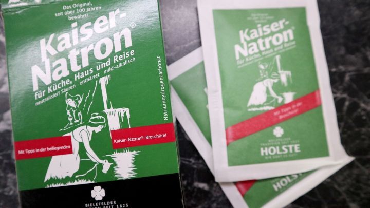 Kaiser Natron-Packung steht auf einer dunklen Oberfl&auml;che, umgeben von einzelnen Portionsbeuteln, die zur Geruchsbek&auml;mpfung dienen.