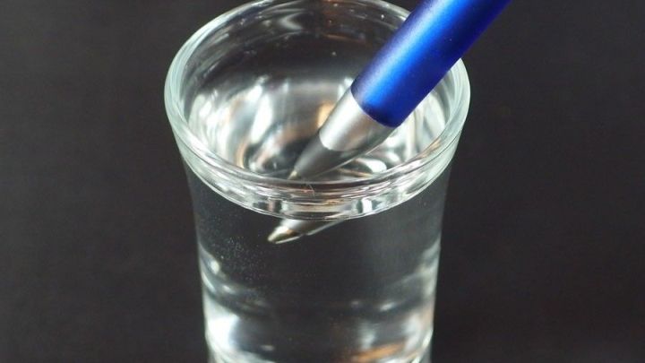 Ein blauer Kugelschreiber taucht in ein Glas warmes Wasser und beginnt wieder zu schreiben.