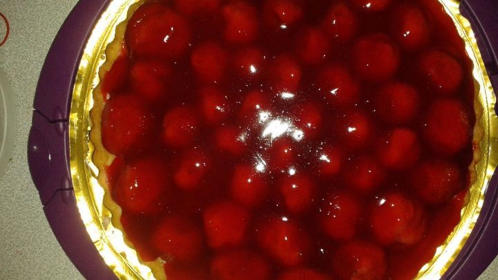 Eine gl&auml;nzende Obsttorte mit frischen Himbeeren, auf einem goldenen Teller pr&auml;sentiert, ideal f&uuml;r einen festlichen Anlass.