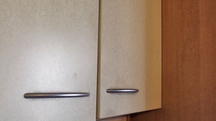 Ein K&uuml;chenschrank mit fettigen Spuren, der durch Sp&uuml;li gereinigt wird, um wieder sauber und gl&auml;nzend zu sein.