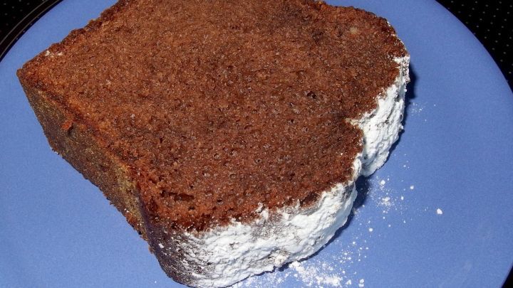 Ein saftiges St&uuml;ck Schokoladenkuchen liegt auf einem blauen Teller, umgeben von einem schlichten Hintergrund.