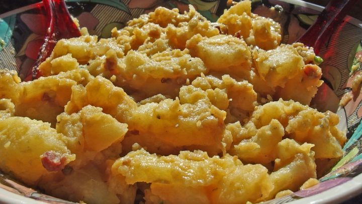 Ein bunter Salat mit Zwiebeln wird in einer Sch&uuml;ssel serviert, die auf einem Tisch im Freien steht.