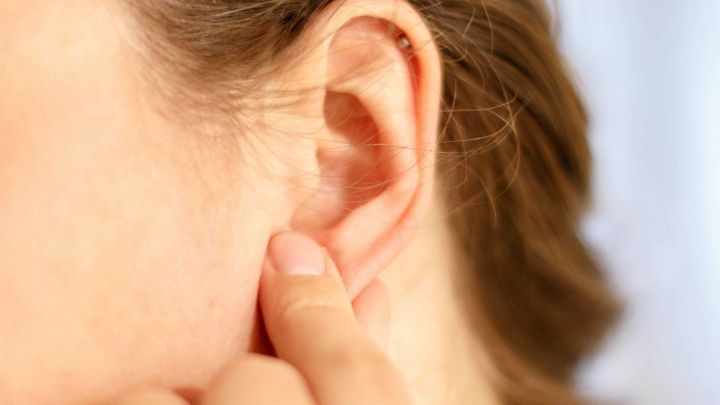 Eine Person massiert das Ohrl&auml;ppchen mit einem Finger in einem entspannenden, ruhigen Umfeld.