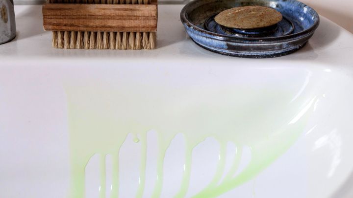 Ein Waschbecken zeigt gr&uuml;ne Farbspuren von Haare f&auml;rben, daneben sind eine B&uuml;rste und eine Schale.