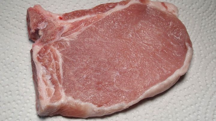 Ein Kotelett liegt auf einer K&uuml;chenoberfl&auml;che, bereit zur Zubereitung in Essigwasser f&uuml;r ein Rezept.