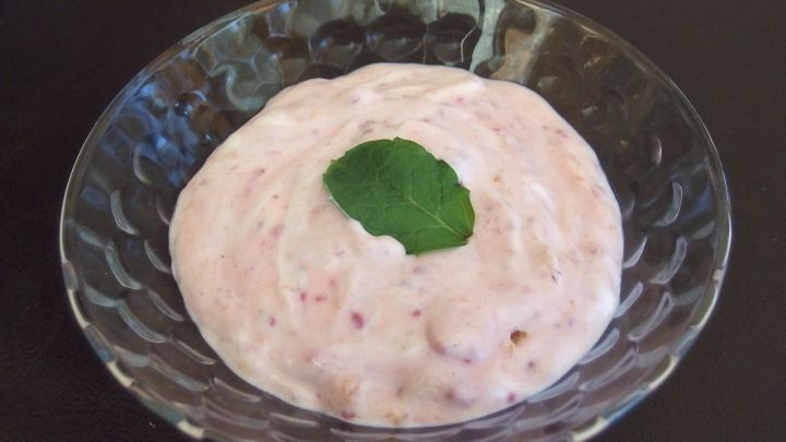 Eine cremige Quarkcreme mit fruchtigem Farbton und einem Blatt Minze in einer transparenten Sch&uuml;ssel.