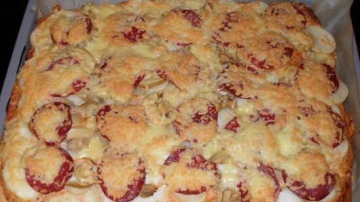 Ein Blechkuchen aus Bratkartoffeln mit einer goldbraunen, knusprigen Kruste und geschnittenen Zwiebeln.