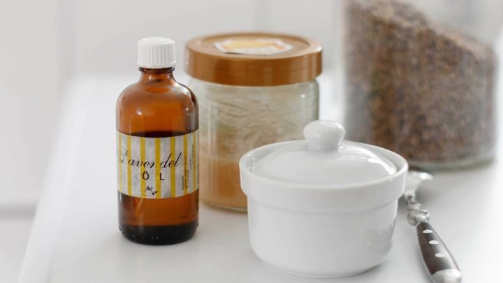 Ein Glasfl&auml;schchen mit Honig steht neben einem wei&szlig;en Beh&auml;lter und einem Holzdeckel, alles auf einem hellen Tisch arrangiert.