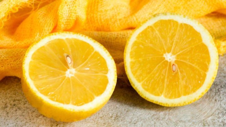 Zwei halbe Zitronen liegen auf einem rustikalen Untergrund, umgeben von gelbem Stoff, der frische und nat&uuml;rliche Pflege symbolisiert.