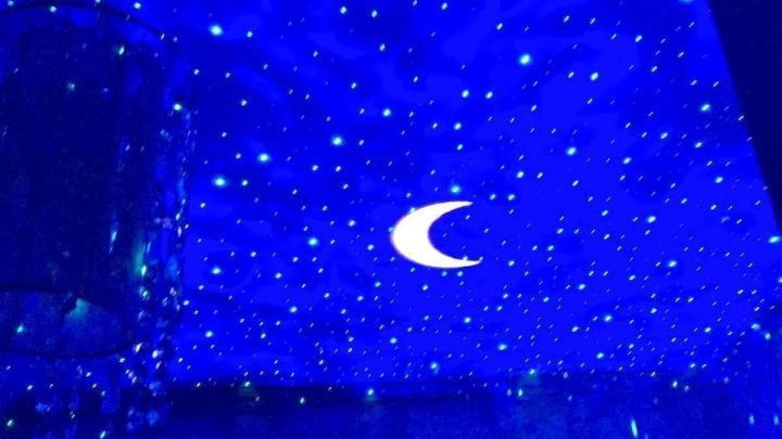Ein blauer Himmel mit Sternen und einem Mond projiziert an die Decke, schafft eine entspannende Atmosph&auml;re zum Schlafen.