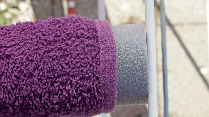 Ein Handtuch mit Staubschutz aus grauer Rohrisolierung wird an einem W&auml;schetrockner befestigt, um Knickfalten zu vermeiden.