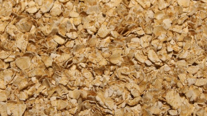 Vollkornhaferflocken liegen lose auf einer Oberfl&auml;che, bereit f&uuml;r die Verwendung in einem Peeling.