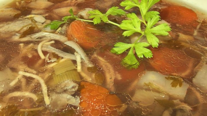 Ein k&ouml;stlicher H&uuml;hnereintopf mit gemischtem Gem&uuml;se schwimmt in einer klaren Br&uuml;he, garniert mit frischem Koriander.