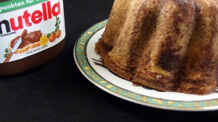 Ein Marmorkuchen steht auf einem Teller neben einem Glas Nutella, bereit, von Nutella-Junkies genossen zu werden.