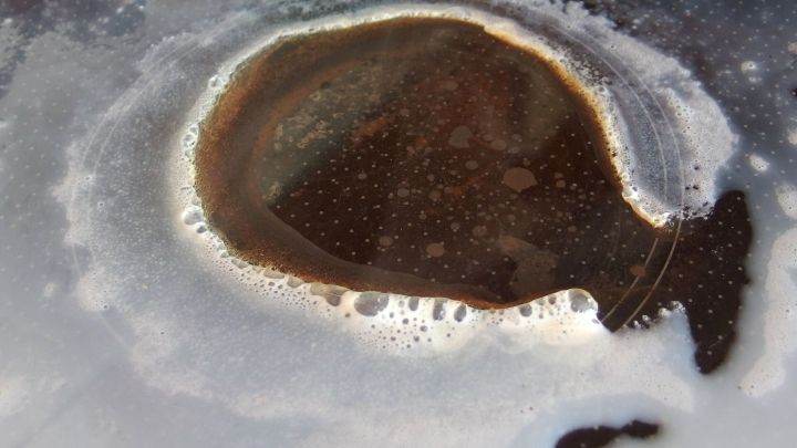 Kochende Milch bildet eine dunkle Blase in der Mitte, w&auml;hrend sich an den R&auml;ndern schaumige &Uuml;berreste absetzen.