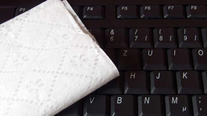 Eine wei&szlig;e Reinigungstuch liegt auf einer dunklen Computertastatur und wird zum schnellen Reinigen verwendet.