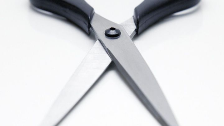 Eine Schere liegt auf einem wei&szlig;en Tisch und ist ge&ouml;ffnet, bereit zum Schneiden von Papier oder Stoff f&uuml;r verschiedene Projekte.