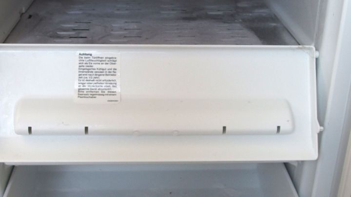Eine wei&szlig;e K&uuml;hltruhe zeigt ein gefrorenes Eisfach, das zum Abtauen bereit ist, um Salz einzuf&uuml;gen.