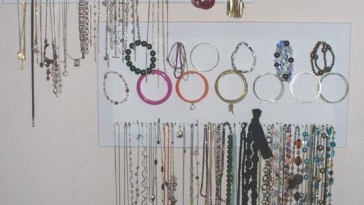 Ohrringe h&auml;ngen an wei&szlig;en Tafeln, ordentlich organisiert in einem Wohnbereich, mit Ketten und Armb&auml;ndern darunter.