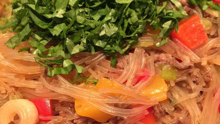 Ein bunter Asiatischer Glasnudelsalat ist mit frischem, gehacktem Gem&uuml;se und Kr&auml;utern garniert.