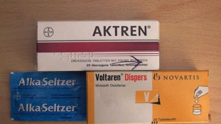 Verschiedene Schmerzmittel, darunter Alka-Seltzer und Voltaren, liegen auf einem Tisch und stehen zur Einnahme bereit.
