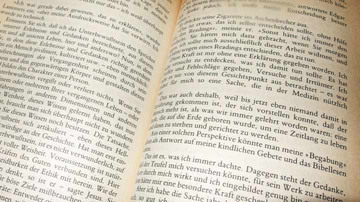 Ein aufgeschlagenes Buch zeigt verklebte Seiten, die Schwierigkeiten beim Lesen verursachen. Die Seiten wirken nass.