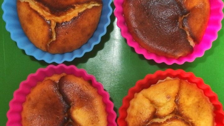 K&auml;sekuchen in F&ouml;rmchen zeigt vier kleine, gebr&auml;unte K&uuml;chlein in bunten Silikonformen auf einer gr&uuml;nen Unterlage.