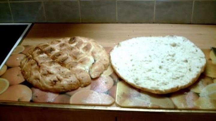 Ein rundes t&uuml;rkisches Fladenbrot liegt auf einer K&uuml;chenarbeitsplatte; die Oberseite ist knusprig, die Unterseite aufgeschnitten.