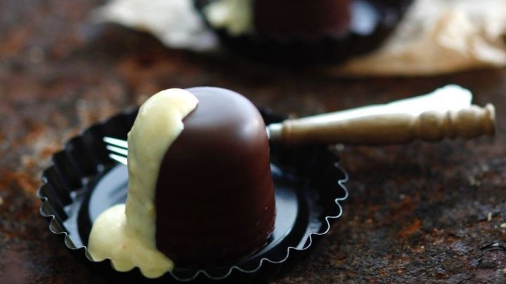 Schokoladenk&uuml;sse stehen auf einem Teller und sind mit Sahne &uuml;berzogen, umgeben von einem rustikalen Hintergrund.