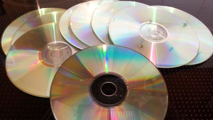 Eine Ansammlung von Gratis-CDs liegt auf einem Tisch, reflektiert Licht und zeigt ihre glatten, farbigen Oberfl&auml;chen.