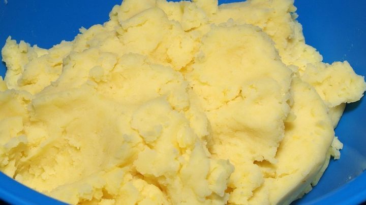 Kartoffelkl&ouml;&szlig;e liegen in einer blauen Sch&uuml;ssel und wirken cremig und frisch zubereitet, bereit zum Servieren.